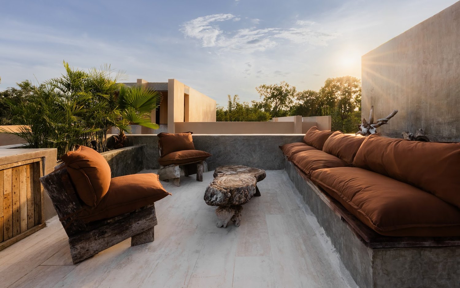 The rooftop lounge at golden hour — sunset, a cigar corner, and the social heart of the house.
